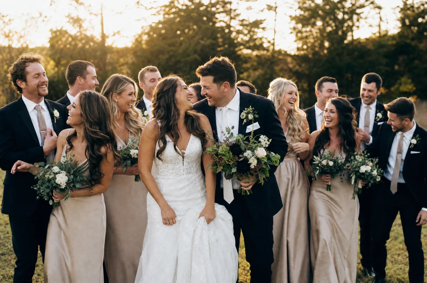 Full bridal party candid group shot, natural laughter, outdoor setting