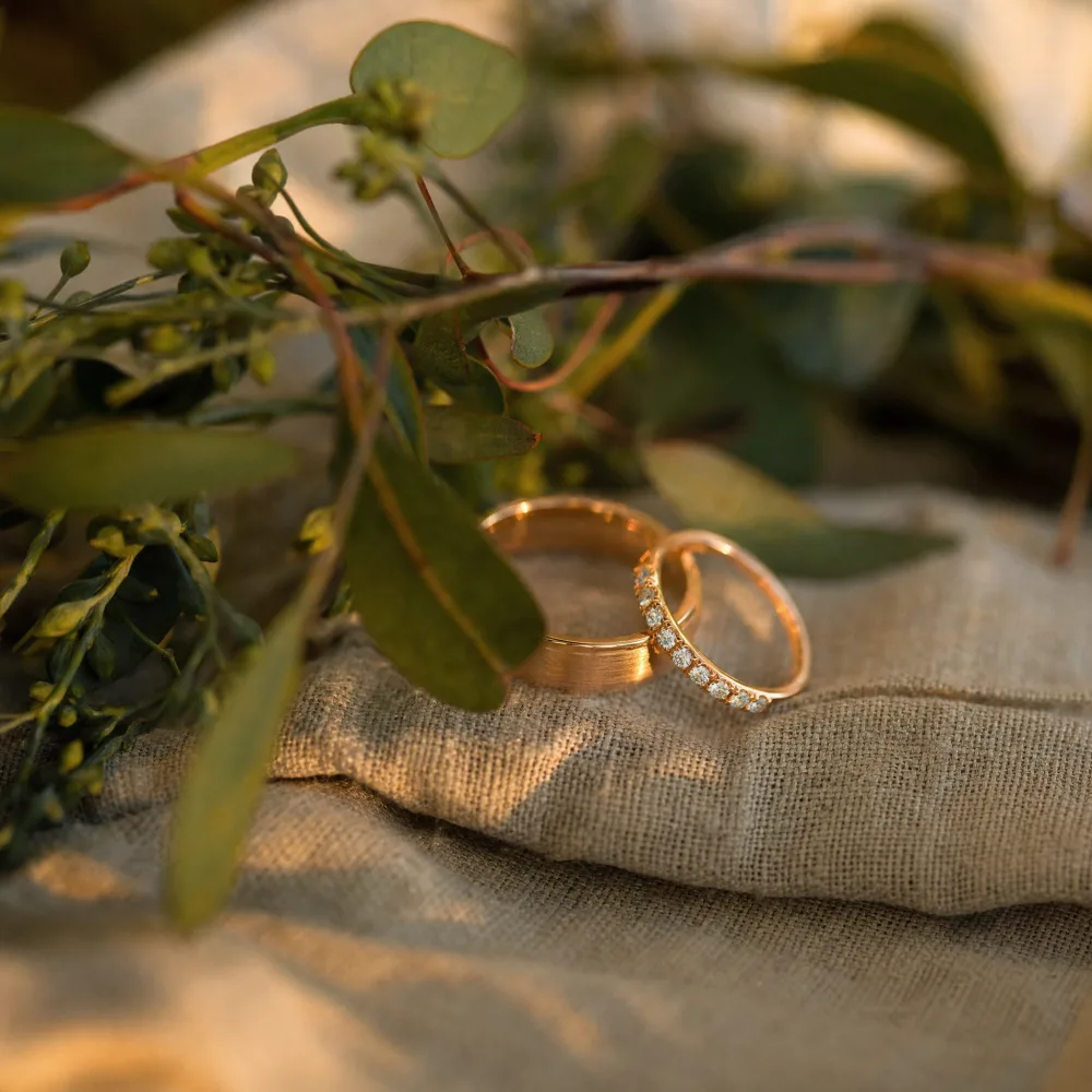 Macro detail of the wedding rings resting on natural linen and greenery