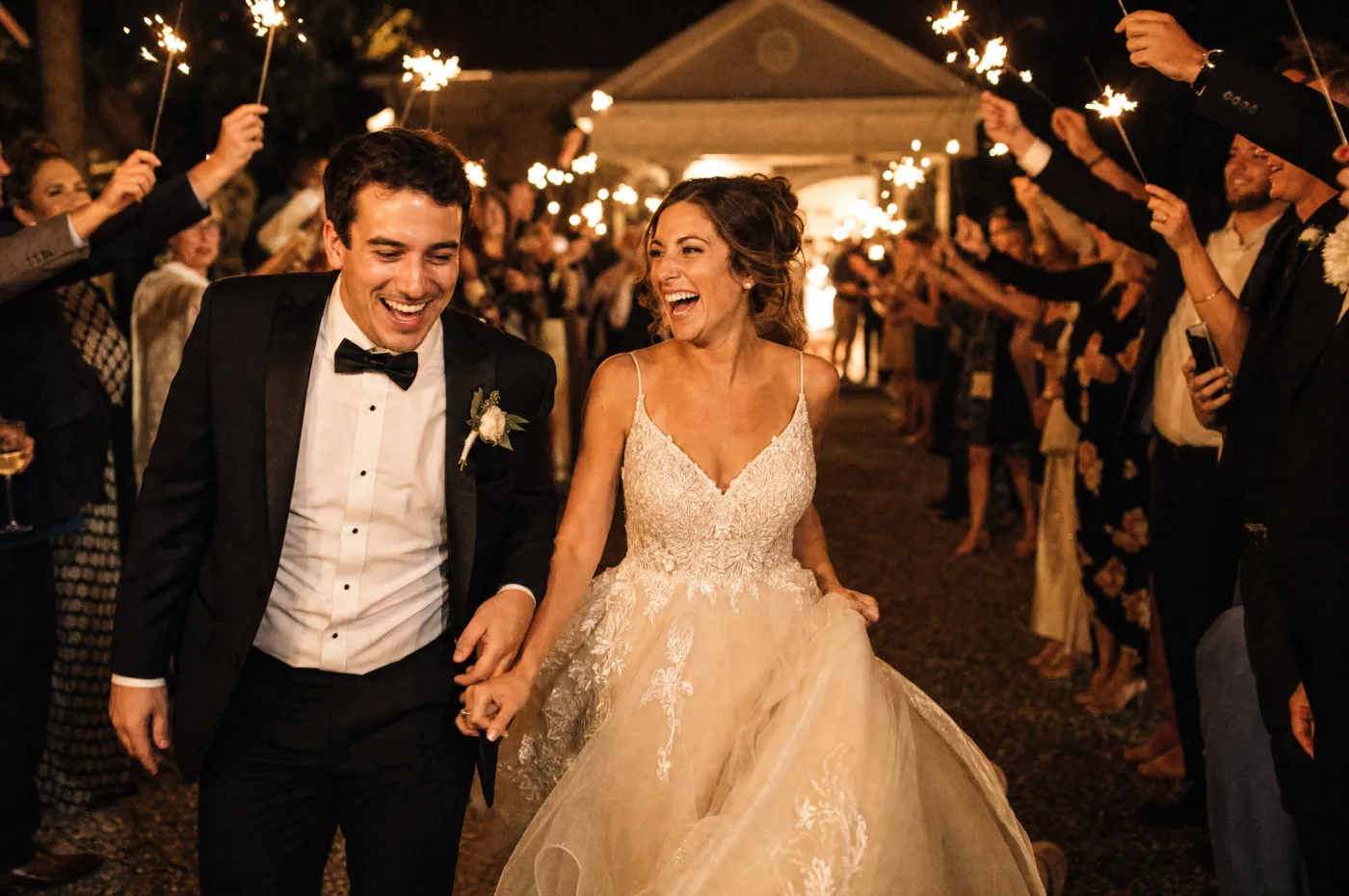 Candid nighttime sparkler send-off as guests cheer the couple on