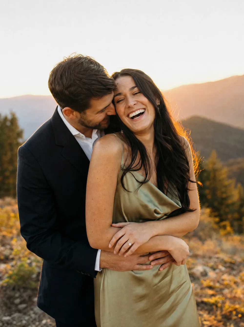 Engaged couple laughing together outdoors during a golden-hour engagement session